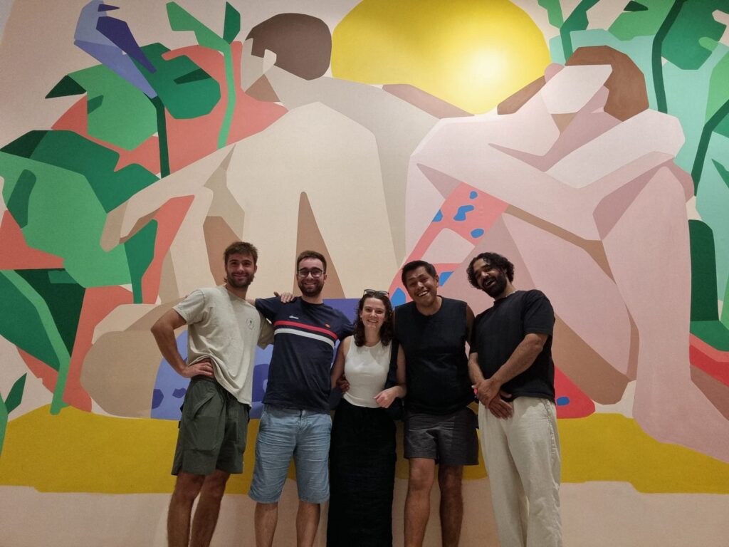 Grupo frente a mural colorido en galería.