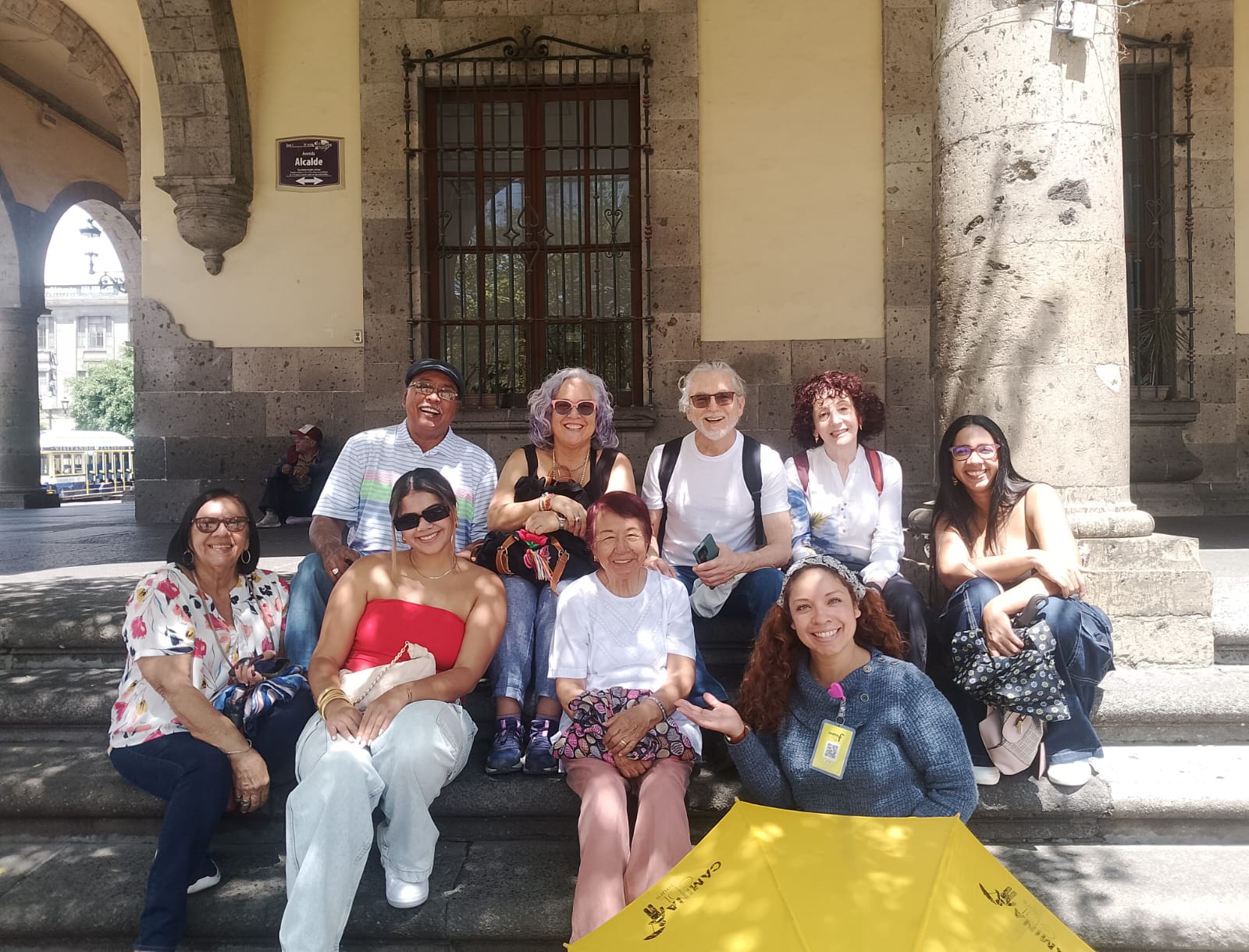 Grupo de personas sonrientes en plaza pública mexicana.