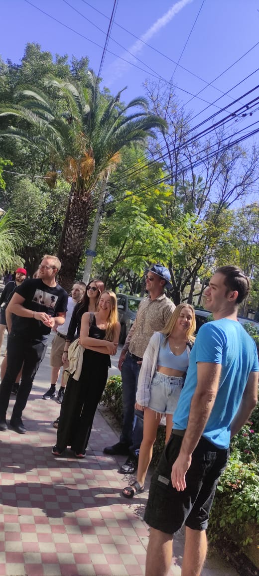 Grupo de personas caminando en una acera soleada.