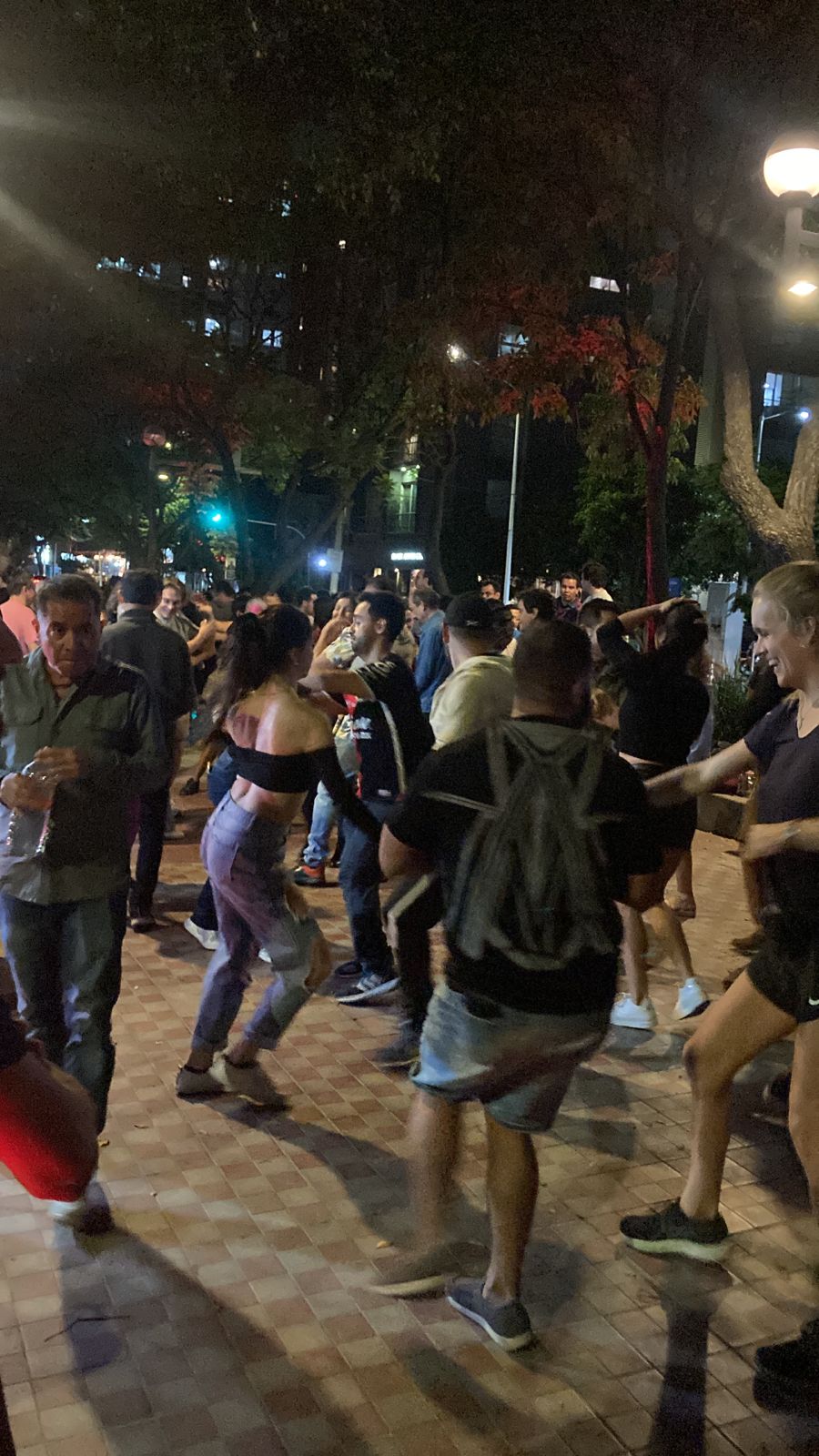 Personas bailando salsa en una plaza.