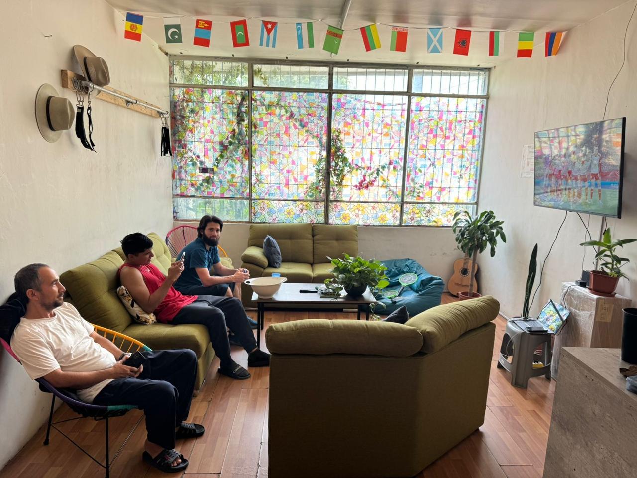 Sala con personas, plantas y banderas decorativas.