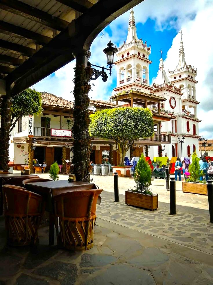 Plaza pintoresca con iglesia colonial y terrazas al aire libre.